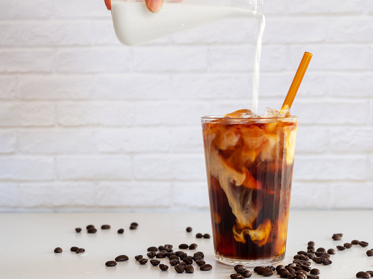 Creamer being poured into cold brew coffee.